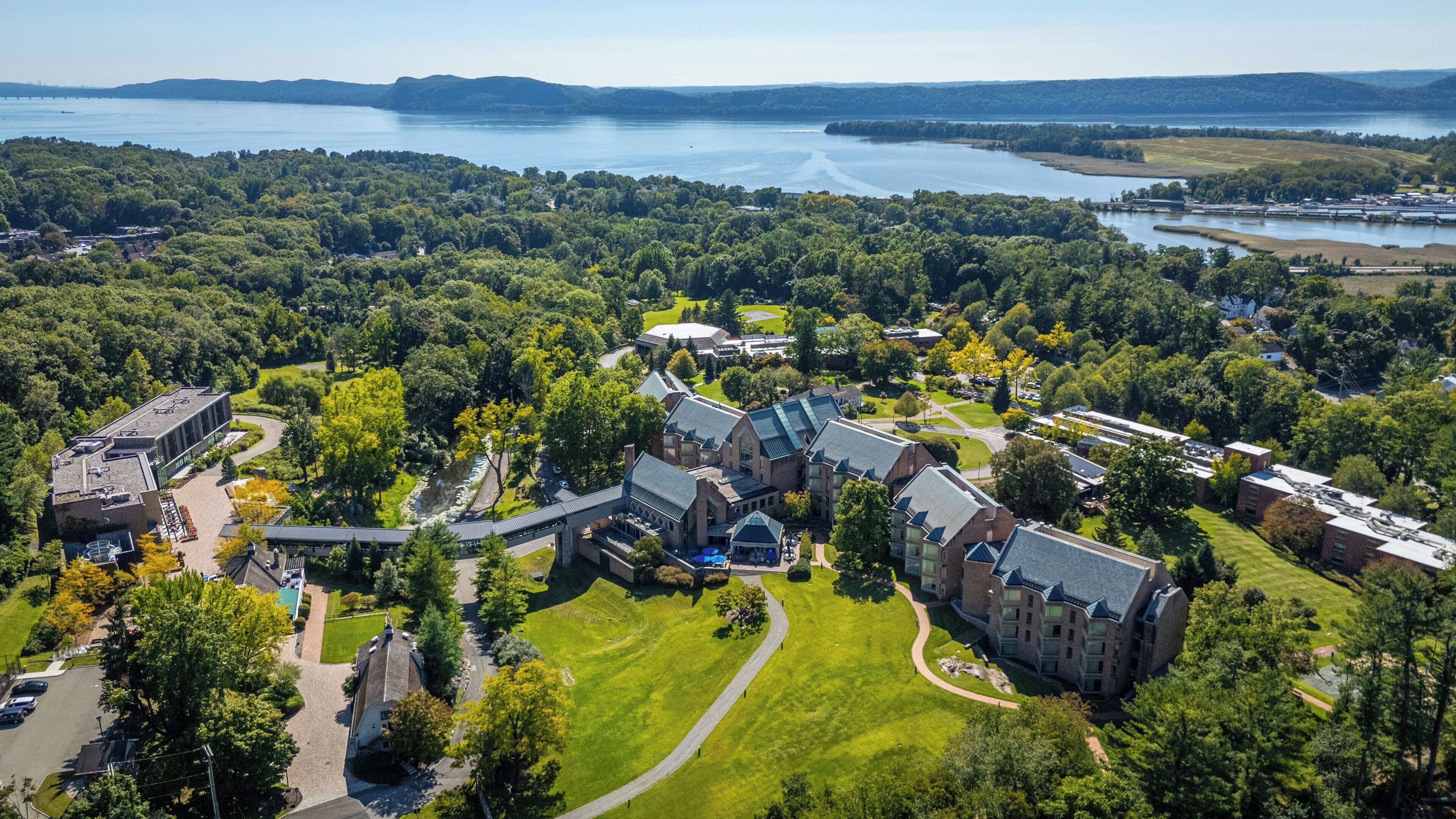 Vue aérienne d’un campus comprenant plusieurs bâtiments, une rivière et des espaces verts environnants.