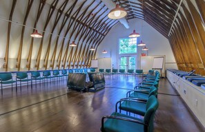 A spacious room with a high arched ceiling and rows of green chairs. - Windrose On Hudson (Ossining)