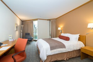 A hotel room with a bed, a desk, a chair, and a view of the outside. - Windrose On Hudson (Ossining)
