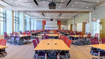 A conference room with multiple tables and chairs, a projector, and a presentation screen.