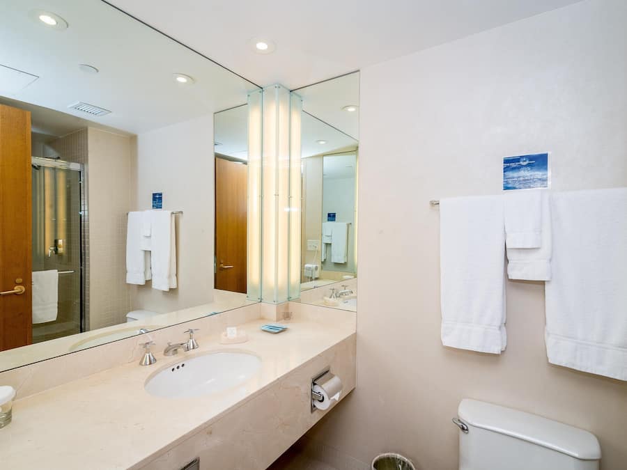 Un bagno moderno con un ampio specchio, due lavabi e un water.