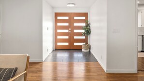 A hallway with wooden flooring, a wooden door with glass panels, and a potted plant. - Edmonds Family Home: Walk to Yost Park, Mins to Beach & Downtown (Edmonds)