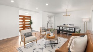 A modern living room with a sofa, armchairs, a coffee table, and a dining area with a table and chairs. - Edmonds Family Home: Walk to Yost Park, Mins to Beach & Downtown (Edmonds)