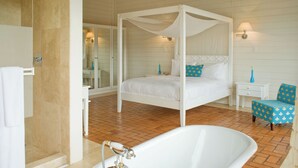 A four-poster bed with a canopy, a white bathtub, and a small bedside table with a lamp. - Asclepios Wellness & Healing Retreat (Tambor)