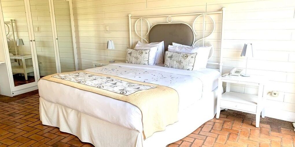 A neatly arranged bedroom with a bed, bedside tables, and a wardrobe.