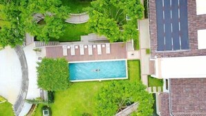 A residential property with a swimming pool, green lawns, and a solar panel. - Asclepios Wellness & Healing Retreat (Tambor)