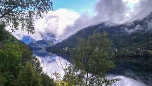 Un paysage montagneux avec un lac, des arbres et un ciel dégagé.