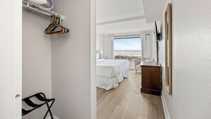 Ein Hotelzimmer mit Bett, kleinem Schreibtisch, Stuhl, Kleiderschrank und Blick auf den Strand.