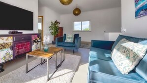A modern living room with a flat-screen TV, a blue sofa, a coffee table, and decorative pillows. - Villa Larissa, luxury private villa, pool (Portimão)