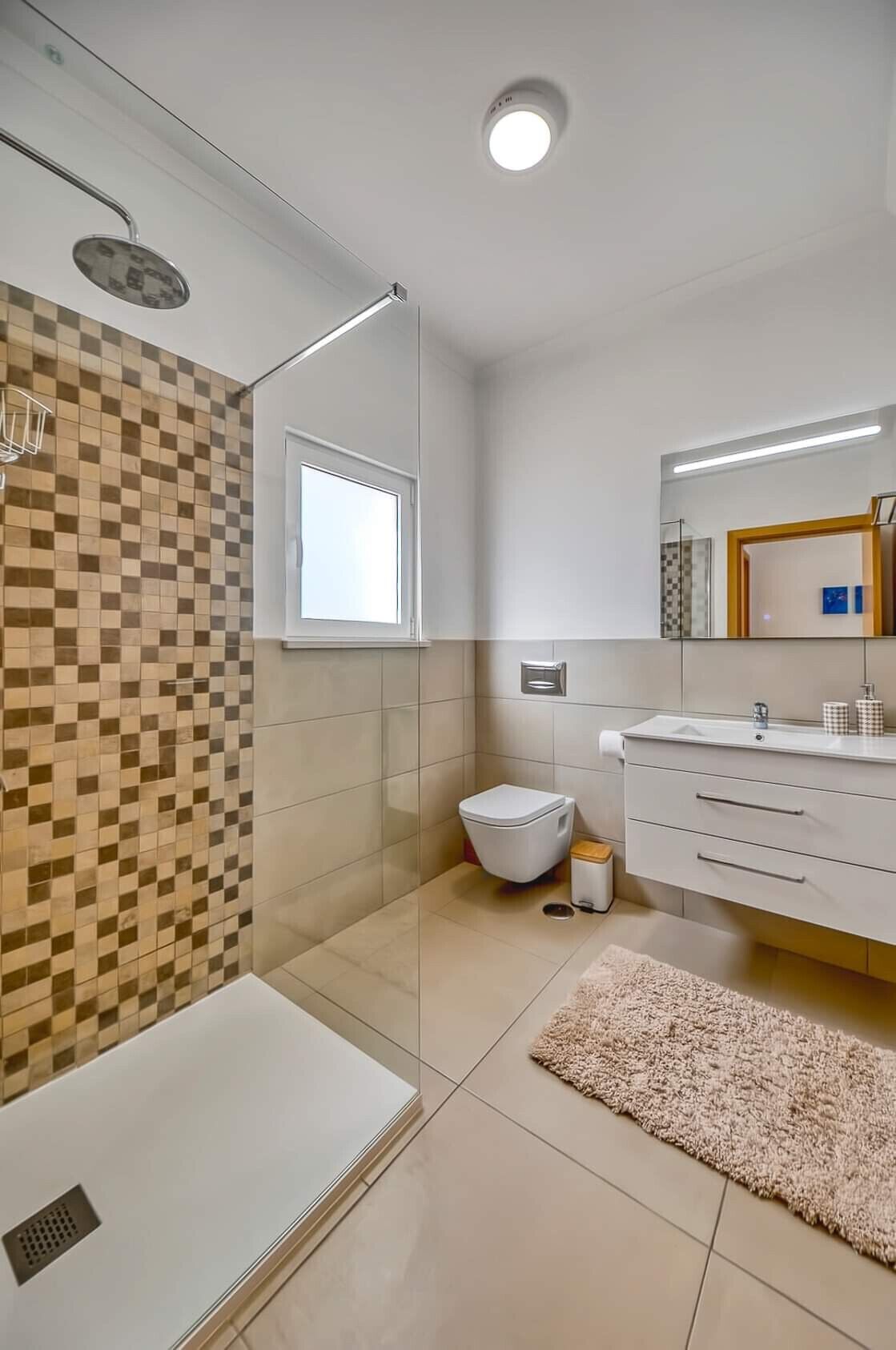 A modern bathroom with a shower, toilet, and vanity.
