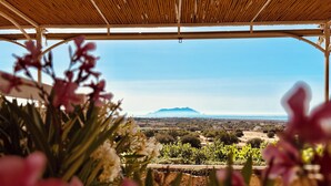 A covered outdoor area with a view of a distant landscape, including a mountain and a body of water. - Alencio Panorama Residence (Favignana)
