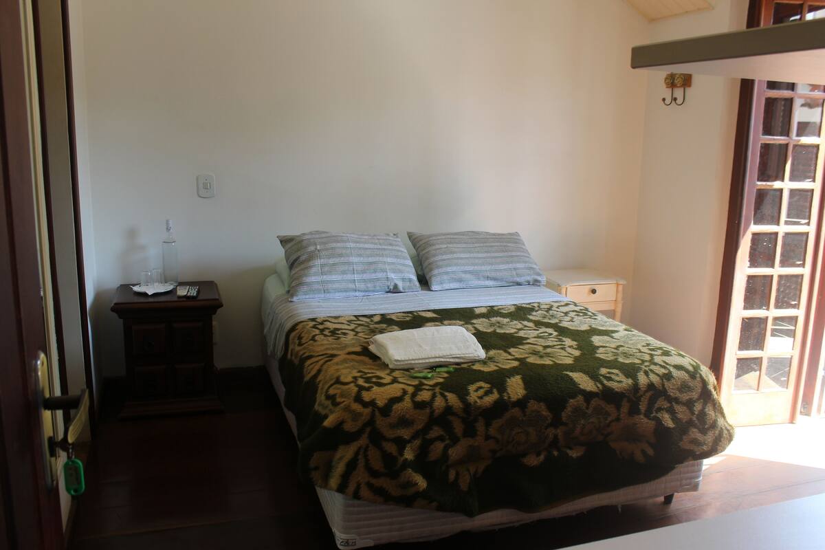 A bedroom with a bed, a bedside table, and a window.