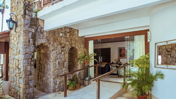 A stone archway leading to a room with a bed and a window. - MANSÃO RESIDENCE HOSPEDARIA E EVENTOS (Vassouras)