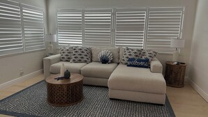 A living room with a beige sofa, patterned cushions, a round coffee table, and a decorative lamp. - Steps from the Beach, Surrounded by Serenity – Your Coastal Getaway Awaits (Ormond Beach)