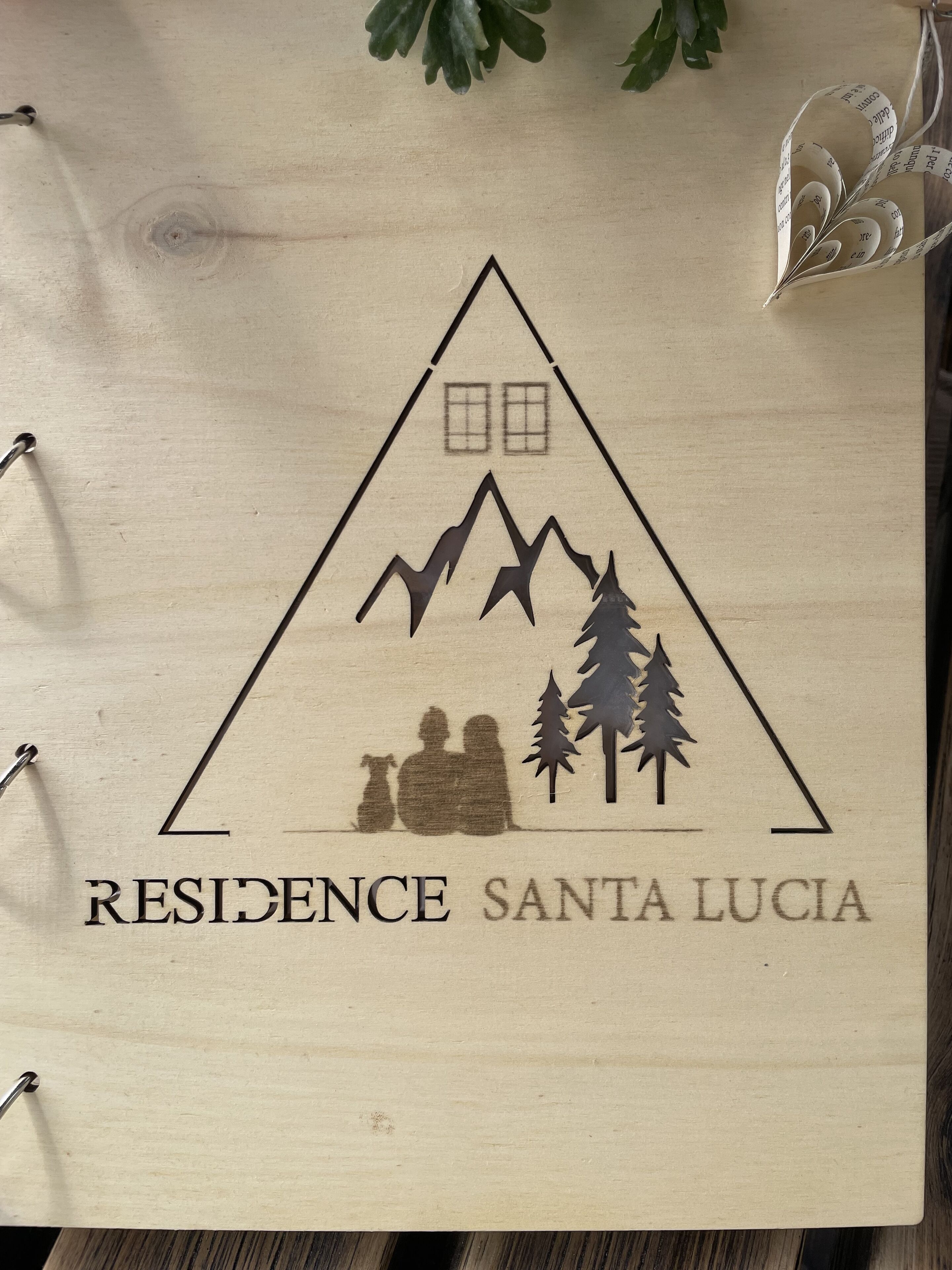 Un letrero de madera con la silueta de una montaña y un árbol, y el texto 
