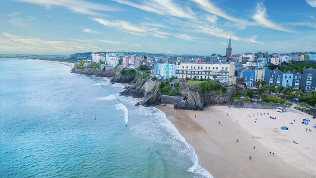 A coastal town with a beach, buildings, and a prominent church spire. - Sandy Steps - 1 Bedroom Apartment - Tenby (Tenby)