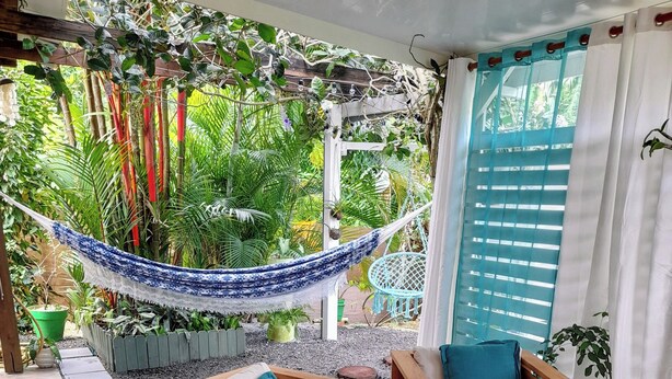 Un patio con muebles de madera, una hamaca y plantas en macetas.