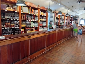 A bar with wooden shelves stocked with various liquor bottles and a counter where a person is serving. - Les Bromélias at Djo and Rosy's, a 2-star vacation rental 🌟🌟 (Sainte-Marie)