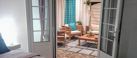 A bedroom with a bed, a bathroom, and a view of an outdoor seating area with a table and chairs.