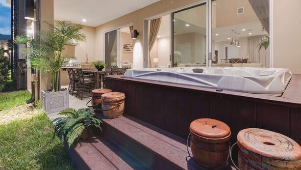 A modern outdoor deck with a hot tub, wooden barrels, and potted plants.