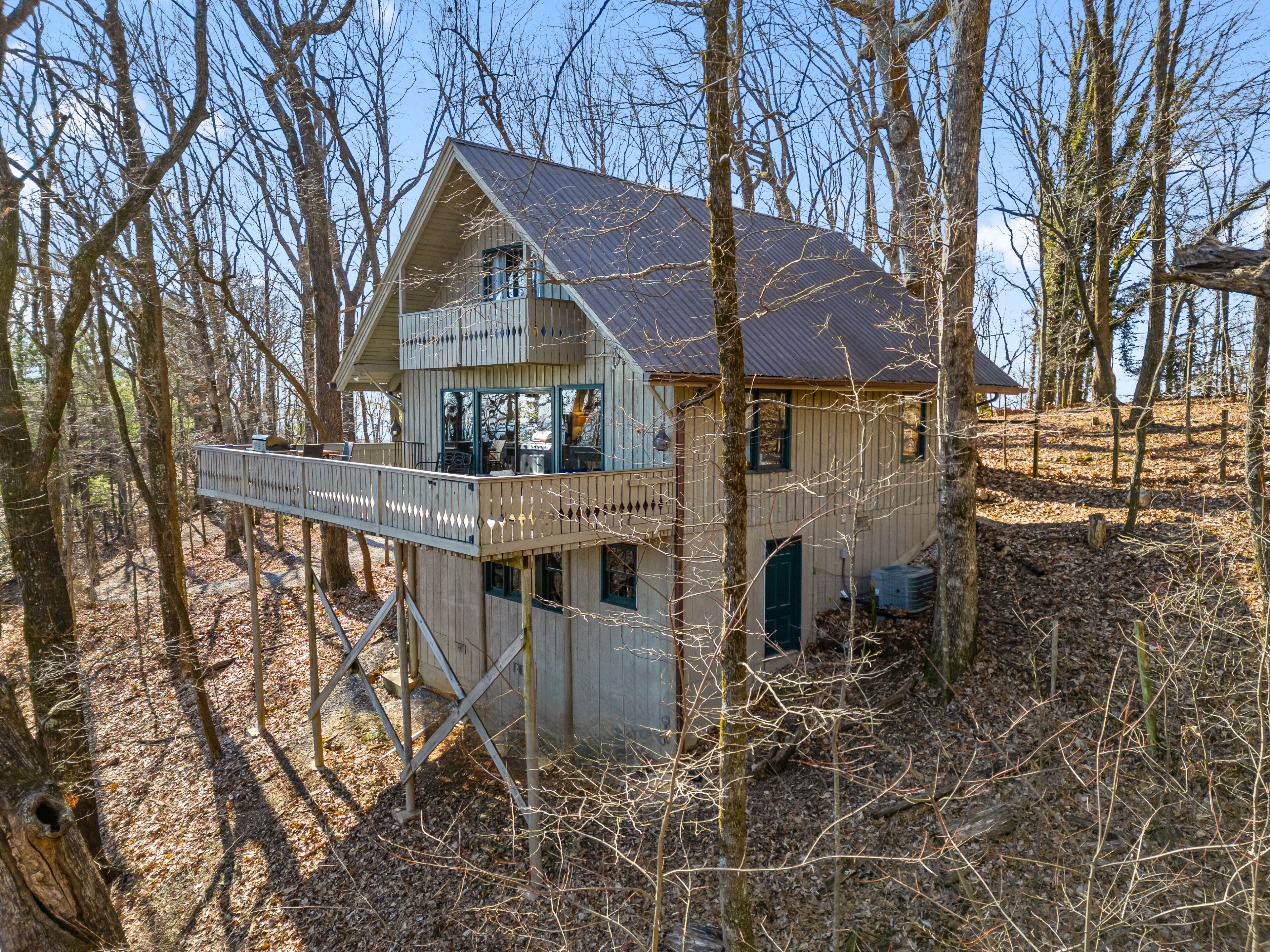 A cabin with a balcony, surrounded by trees.