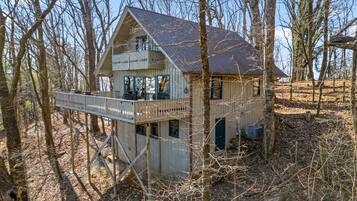 A cabin with a balcony, surrounded by trees.