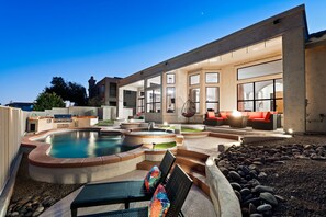 Ein moderner Poolbereich im Freien mit Whirlpool, Sitzgelegenheiten und einer gepflegten Landschaft.