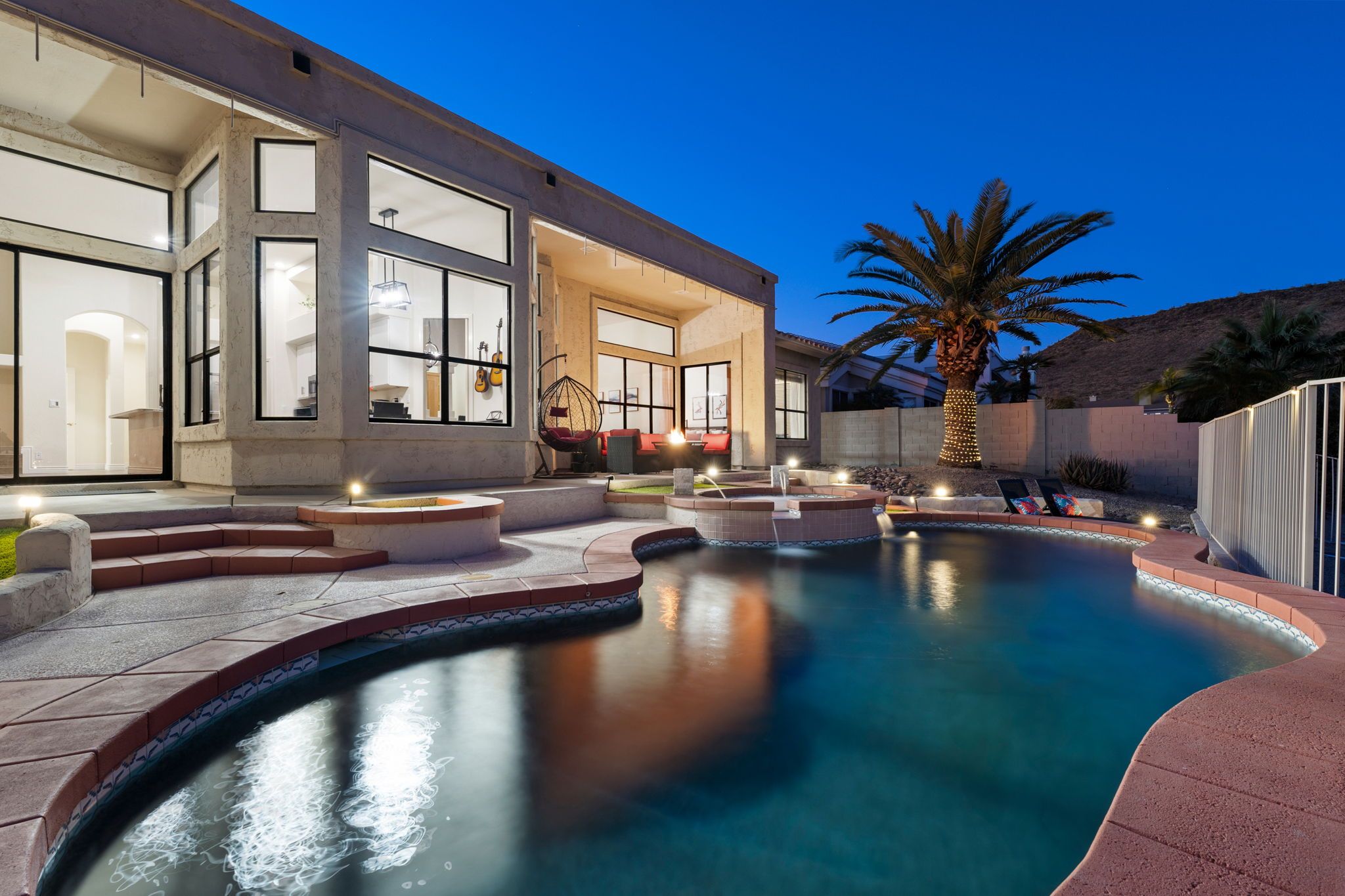 A modern house with a swimming pool, outdoor seating, and a large window overlooking the pool.