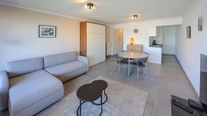 Un salon moderne avec un canapé, une petite table et un coin cuisine à l’arrière-plan.
