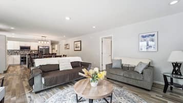 A modern living room with a sofa, a coffee table, and a dining area.