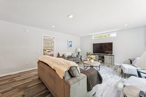 A modern living room with a sofa, a coffee table, a TV, and a fireplace.