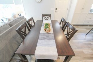 Un comedor con una mesa larga, sillas, un centro de mesa decorativo y un sofá.