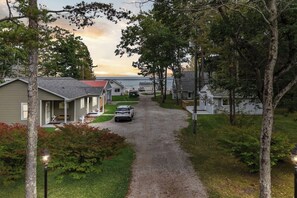 A residential street with houses, a gravel driveway, and a car parked in the middle.
