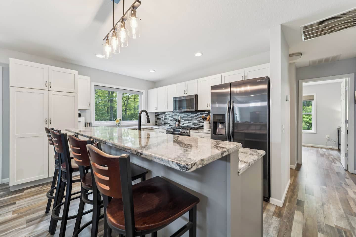 A modern kitchen with a central island, stainless steel appliances, and a view to the outdoors.