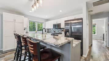 A modern kitchen with a central island, stainless steel appliances, and a view to the outdoors.