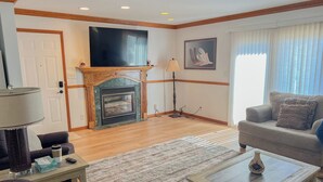A living room with a fireplace, a sofa, a coffee table, and a television. - The biggest cottage at Sunnyside — newly remodeled, 4BR/3BA, sleeps up to 10. (Greenbush)