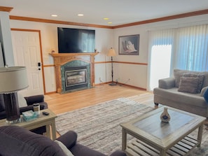 A living room with a fireplace, a sofa, a coffee table, and a television. - The biggest cottage at Sunnyside — newly remodeled, 4BR/3BA, sleeps up to 10. (Greenbush)