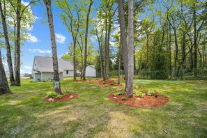 A residential property with a house, a garage, and a well-maintained lawn with trees and shrubs. - The biggest cottage at Sunnyside — newly remodeled, 4BR/3BA, sleeps up to 10. (Greenbush)