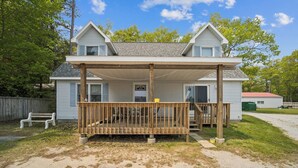 A two-story house with a covered porch and a front door. - The biggest cottage at Sunnyside — newly remodeled, 4BR/3BA, sleeps up to 10. (Greenbush)