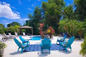 Un espace piscine doté de chaises longues, d’un gazebo et de plantes tropicales.
