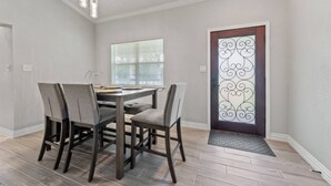 A dining area with a table and chairs, a window with blinds, and a decorative door with a metal design.