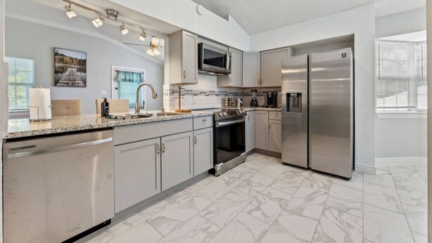 A modern kitchen with stainless steel appliances, granite countertops, and a large island.