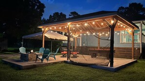 An outdoor patio area with string lights, wooden furniture, and a covered seating area.
