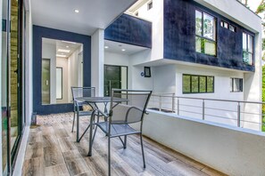 A modern building with a balcony, a table with chairs, and a view of the greenery. - 7-Bedroom Mansion in Escazú featuring Covered Heated Pool, Jacuzzi, & Full AC. (Escazu)