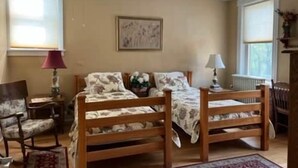 A bedroom with two wooden beds, a chair, a table, and a ceiling fan.