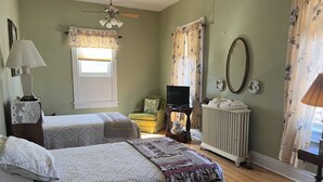Een kamer met twee bedden, een televisie, een radiator en een raam met gordijnen.