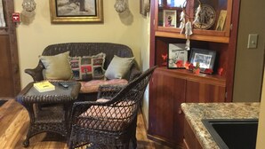 Una sala acogedora con un sofá de mimbre, una mesita y un aparador con objetos decorativos.