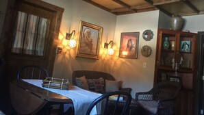 Una habitación acogedora con techo de madera, una mesa de comedor con sillas, un sofá e iluminación en la pared.