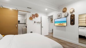 Un dormitorio con una cama grande, un televisor en la pared y una escena de playa en la pantalla.