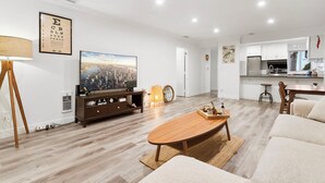 Un moderno salón con una mesa de centro de madera, un televisor y un cuadro de un paisaje urbano.